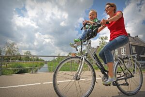 Moeder met kind fietsend op een fiets met een moederstuur.