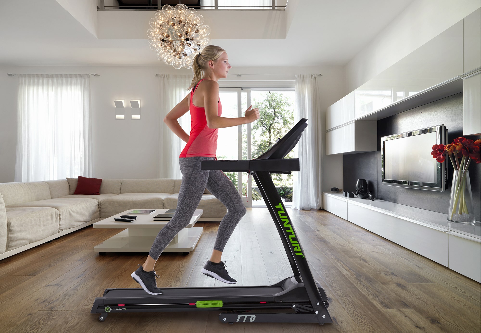 Tunturi loopband - looptrainer Vrouw in sportieve kleding trainend op Tuntur T10 loopband in luxe woonkamer.
